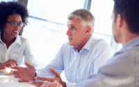 Three people are seated at a table talking