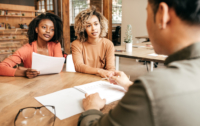 Three people around a desk, paperwork